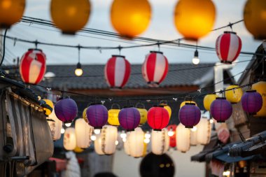 Renkli fenerler hareketli bir pazar caddesinde asılı, akşam atmosferini aydınlatıyor ve kültürel cazibe ve eşsiz güzellikle dolu canlı bir sahne yaratıyor..
