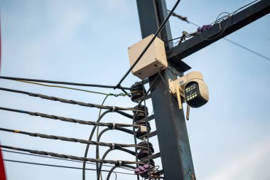 Elektrik direğine monte edilmiş bir güvenlik kamerası görüntüsü. Güvenlik ve izleme amacıyla şehir altyapısını ve modern teknolojiyi vurguluyor..
