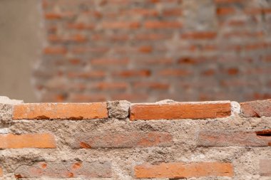 Kırsal tuğla bir duvarın yakın plan görüntüsü, desenli yüzeyler ve tasarım veya mimari projeler için uygun sıcak turuncu renkler..