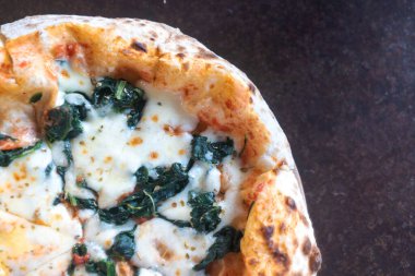 Bu resimde mozzarella peyniri ve ıspanakla kaplanmış taze pişmiş bir pizza var. Lezzetli bir kabuk ve davetkar bir doku sergiliyor. Çeşitli mutfak kullanımları için mükemmel..