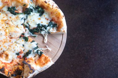 Taze ıspanak ve erimiş peynirle kaplı lezzetli bir dilim pizzanın tadını çıkar, ahşap bir tahtada servis edilir, her yemek ve atıştırmalık için mükemmeldir..