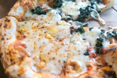 Bu resim erimiş peynir ve ıspanakla kaplı taze bir pizzayı gösteriyor. Kabuğu altın kahverengidir, davetkar ve her yemek için mükemmeldir..