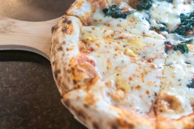 Taze ıspanakla kaplanmış lezzetli bir peynirli pizzanın yakın çekimi, kabuğu ve lezzetli malzemeleri vurgulamak, aşçılar ve yemek severler için mükemmel..