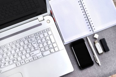 Office çalışma alanı ile cep telefonu ve dizüstü bilgisayar klavye kadar yakın ve fare ile defter görünümünü yukarıda yüksek, kalem ve usb flash gri masanın üzerinde. Çalışma bloglama Resepsiyon Masa kavramı 