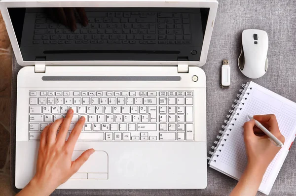 İnsan eli ile izole perde beyaz dizüstü klavye yazarak. Çalışma Resepsiyon Masa kavramı. Görünümü fare ile defter ve ofis işyeri telefon ile yukarıda yüksek, kalem ve usb flash gri masanın üzerinde.
