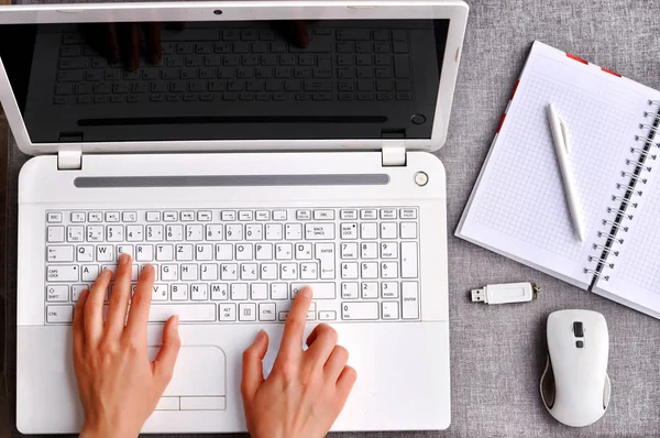 İnsan eli ile izole perde beyaz dizüstü klavye yazarak. Çalışma Resepsiyon Masa kavramı. Görünümü fare ile defter ve ofis işyeri telefon ile yukarıda yüksek, kalem ve usb flash gri masanın üzerinde.