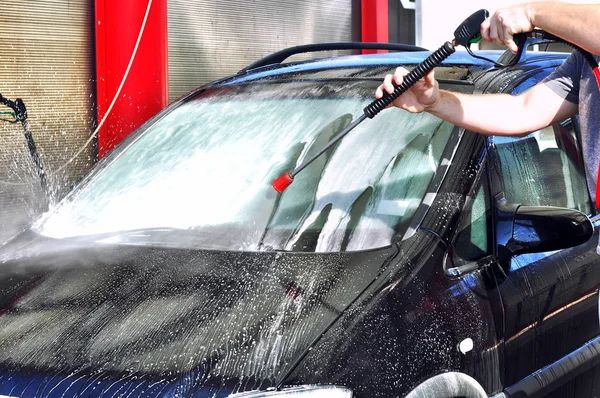 Cleaning Car Using High Pressure Water. Man washing his car under high pressure water in service