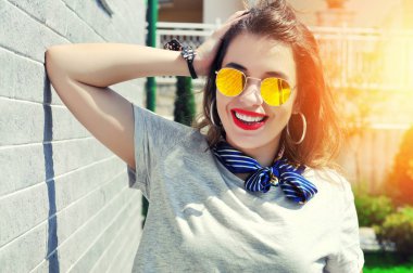 Yaz şehir vibes. Güneşli yaşam tarzı moda portre oldukça genç gülümseyen kadın moda kıyafet güneş gözlüğü kırmızı ruj gri arka plan üzerinde var  