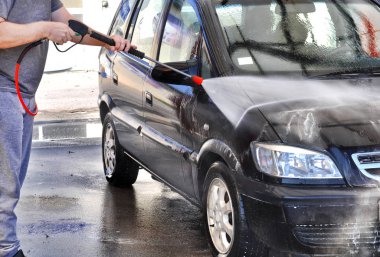 Yüksek basınçlı su kullanarak araba temizlik. Adam arabasını yüksek basınç su altında hizmetinde yıkama