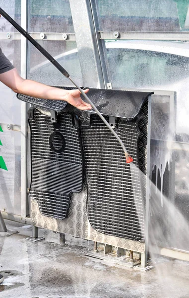 Washing car mats with high pressure water in car wash