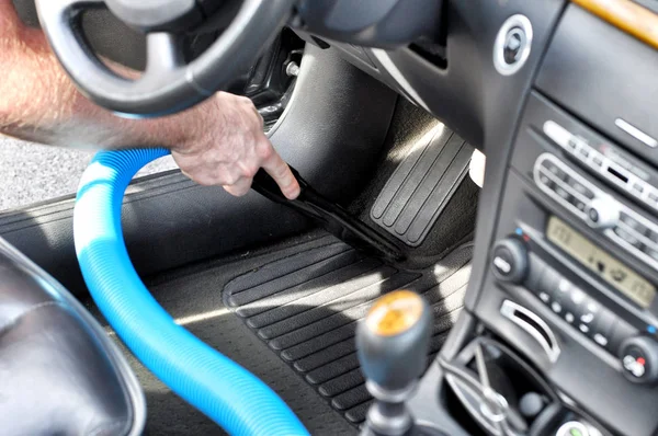 Man cleaning the interior of the car with vacuum cleaner