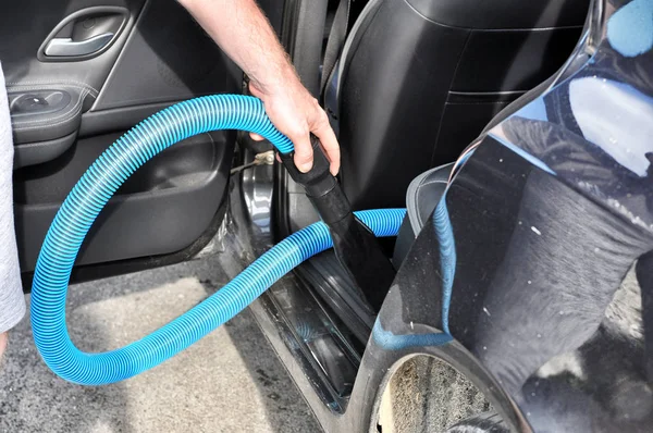 Man cleaning the interior of the car with vacuum cleaner