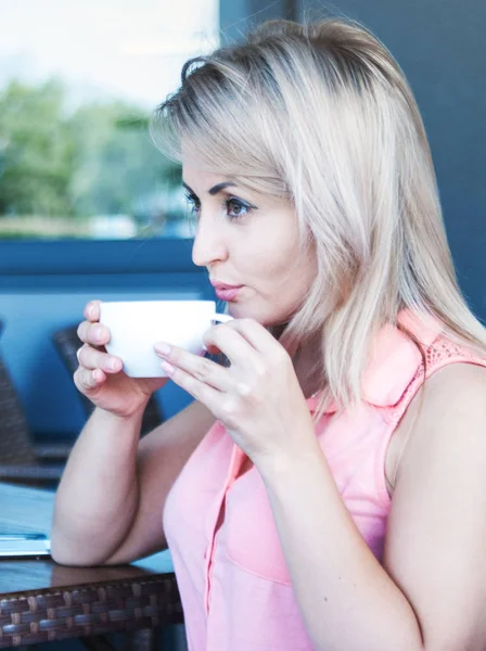 Pretty woman drinks coffee outdoor.