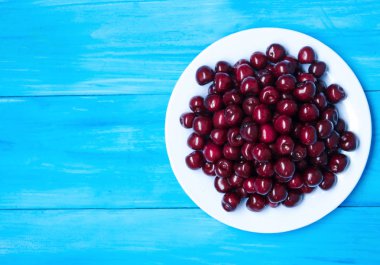 Mavi renkli bir tabağa olgun kiraz. 