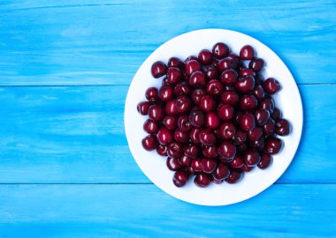 Mavi renkli bir tabağa olgun kiraz. 