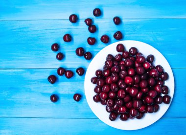 Mavi renkli bir tabağa olgun kiraz. 