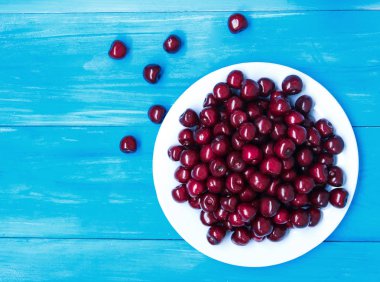 Mavi renkli bir tabağa olgun kiraz. 