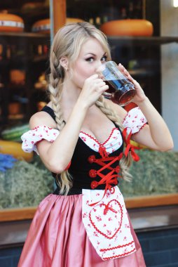 Güzel kadın içecekler bira Octoberfest elbiseli. 