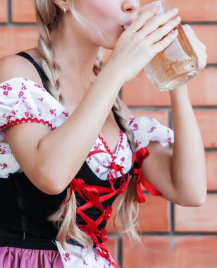 Güzel kadın içecekler bira Octoberfest elbiseli. 