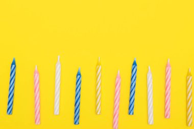 Sarı arka plan üzerinde renkli mumlar. 