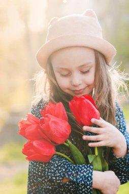 Sevimli küçük kız bir buket bahar laleler. 
