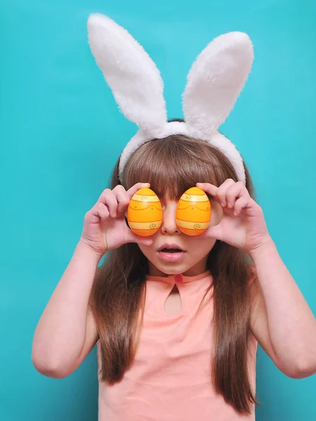 Cute little girl with the bunny ears holds eggs. Happy Easter.