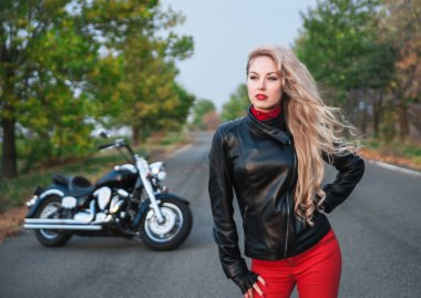 Bir motosiklet üzerinde yol ile poz bir şık motorcu kadın.