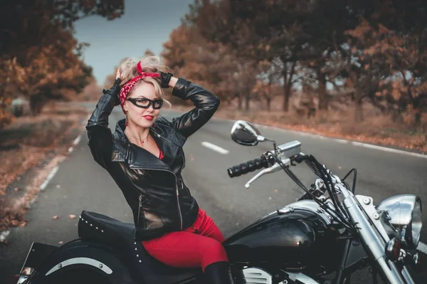 A stylish woman with motorcycle on the road. Pin-up style.