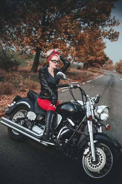 A stylish woman with motorcycle on the road. Pin-up style.