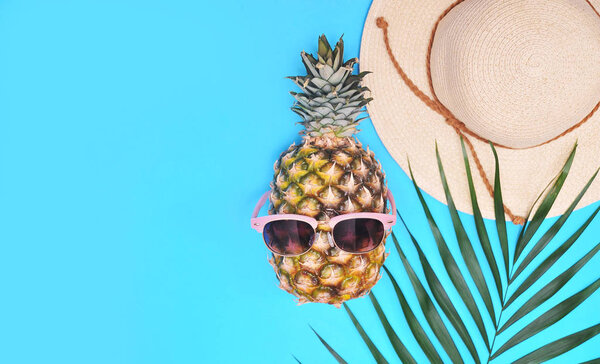 Palm leaf, pineapple and hat. Summertime background. Vacation concept.