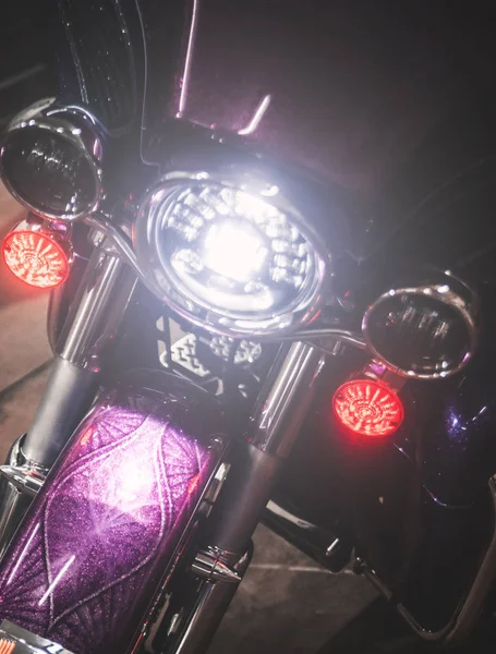 Headlight on violet motorcycle.