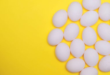Sarı arka plan üzerinde beyaz Paskalya yortusu yumurta.