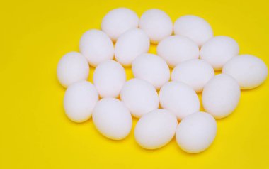 Sarı arka plan üzerinde beyaz Paskalya yortusu yumurta.