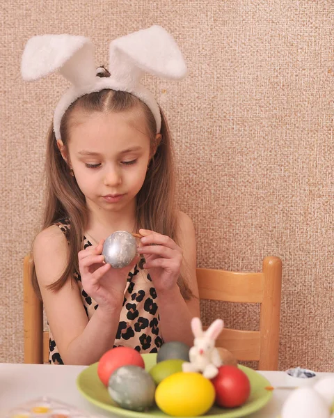 Cute little girl painting easter eggs at home.