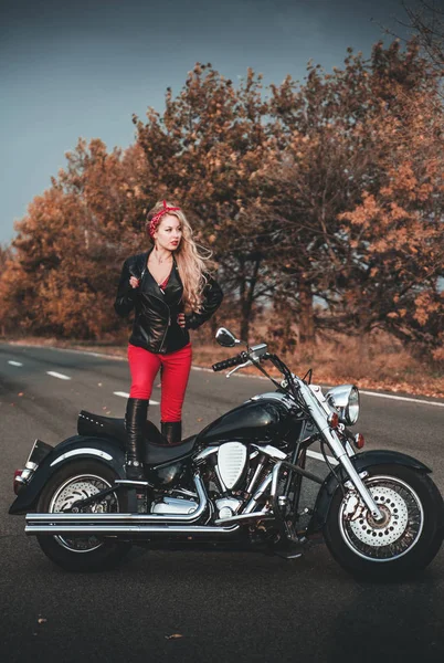 Biker woman with motorcycle on the road.