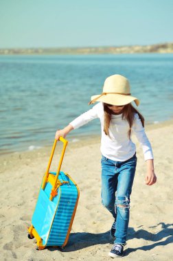 Sahilde bavul ile şapka sevimli küçük kız. Summertime kavramı.