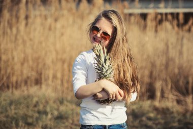 Gün batımında sahilde ananas ile küçük sevimli kız.