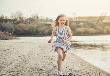 Sevimli küçük kız gün batımında sahilde bir eğlence var.