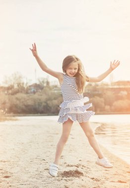 Sevimli küçük kız gün batımında sahilde bir eğlence var.