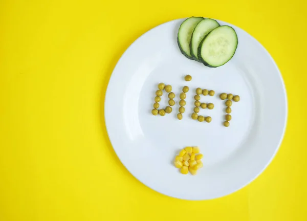 Conceptual image of diet theme. Plate with some food. The word diet made from peas.