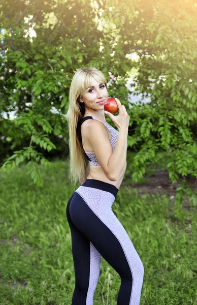 Beautiful fitness woman makes exercises outdoors.