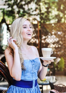 Güzel genç kadın latte fincan ile kafein poz.
