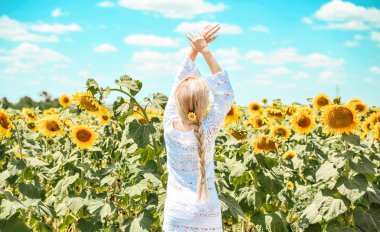 Güzel beyaz kadın ayçiçeği ile çayırda poz.