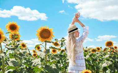 Beyaz elbiseli güzel beyaz kadın çayırda ayçiçekleriyle poz veriyor..