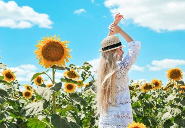 Güzel beyaz kadın ayçiçeği ile çayırda poz.