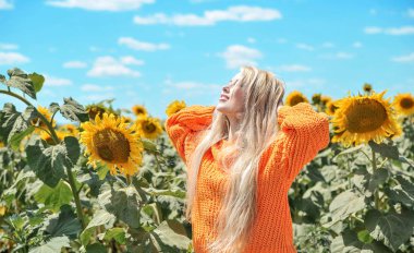 Güzel beyaz kadın ayçiçeği ile çayırda poz.