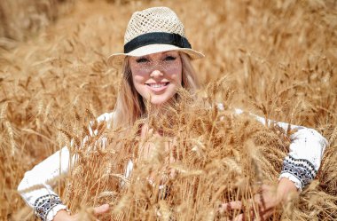 Güzel beyaz kadın çayırda buğdayla poz veriyor..