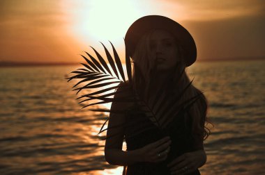 Elinde palmleaf ile şapka güzel şık kadın sahilde bir eğlence var.