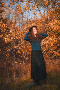 Sonbahar geçmişinde kızıl saçlı kadın. Kızıl saçlı kadının moda portresi.