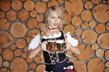 Elinde bira ile gülümseyen güzel kadın ahşap arka plan üzerinde poz. Oktoberfest konsepti.